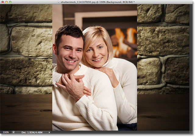 Young couple hugging on sofa in front of fireplace. Image licensed from Shutterstock by Photoshop Essentials.com