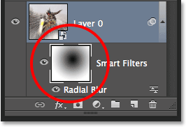 The Smart Filter mask thumbnail in the Layers panel showing the black to white radial gradient. Image © 2013 Photoshop Essentials.com