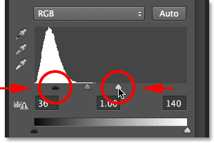 Dragging the black point and white point sliders in Levels. Image © 2013 Photoshop Essentials.com