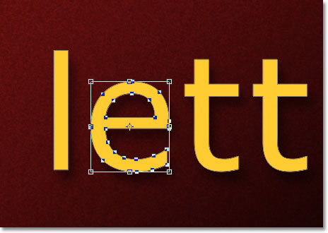 The Free Transform bounding box and handles appears around the letter. Image © 2011 Photoshop Essentials.com.